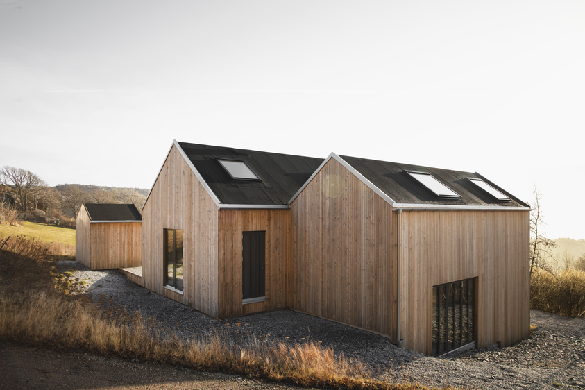Wood-clad home with calm roof form and broad window openings