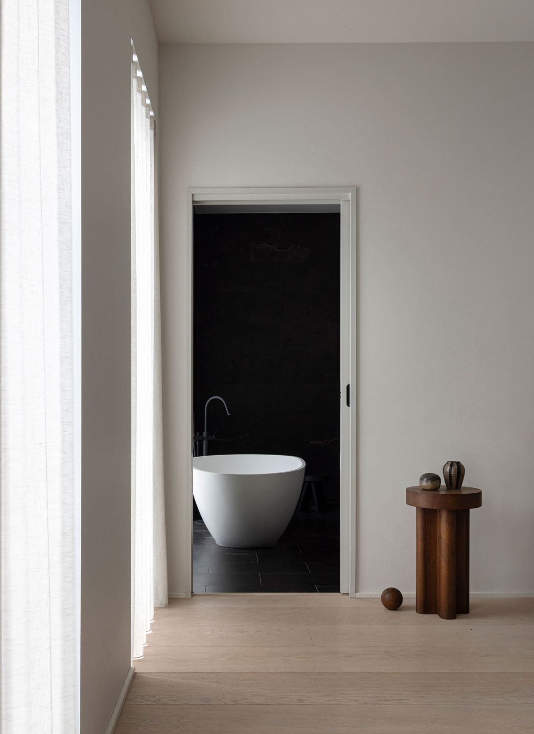 Light bathroom with freestanding tub, pale surfaces, and calm material transitions