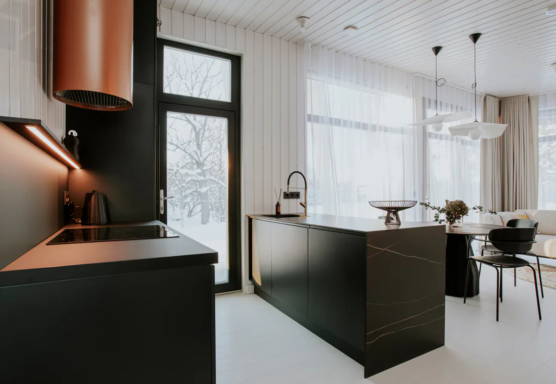 Kitchen remodel with dark cabinetry, copper range hood, island, and bright window light