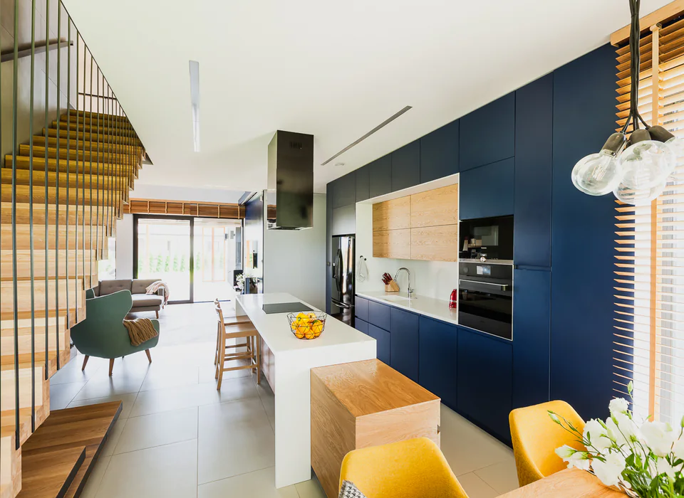 Kitchen and living area with dark cabinets, wood stair, and bright daily-use space
